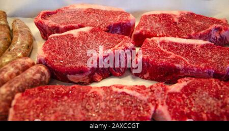 New York Strip steaks on a board with salt and pepper. Raw sausages. Barbecue. Stock Photo
