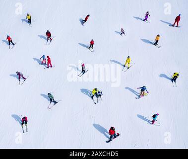 Many skiers and snowboarders are located on the side of the mountain Stock Photo