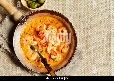 Scampi fried in fat with garlic and chili served in an old skillet on a rustic table with copy space in a top down view Stock Photo