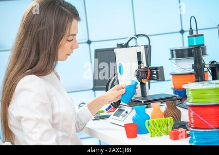 Young female designer works with a 3D printer in a design studio Stock Photo