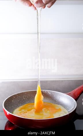 Preparing scrambled eggs - sticking the eggs in the pan Stock Photo
