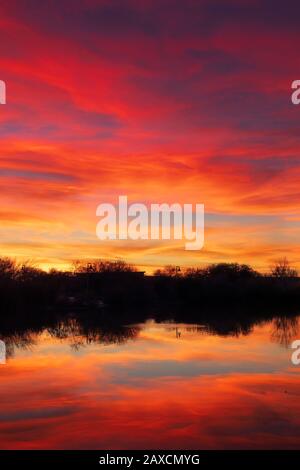 Colorful sunset sky and dramatic clouds with reflection in a lake Stock Photo