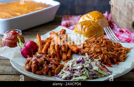 Southern US cooking. Vegan barbecue jack-fruit, coleslaw, oven baked spicy sweet potatoes and BBQ baked beans. Stock Photo