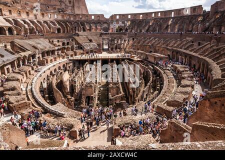 A wide angle view of the interior of the Colosseum in Rome, Italy with tourists wandering about.