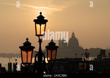 Lanterns in front of sunset behind Santa Maria della Salute in Venice (Italy) Stock Photo