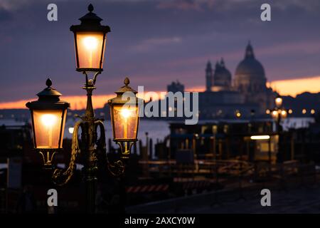 Lanterns in front of sunset behind Santa Maria della Salute in Venice (Italy) Stock Photo