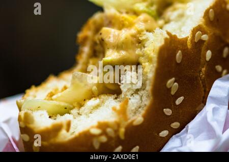 Close up detail of a bitten cheeseburger. Food, junk food and fast food concept Stock Photo