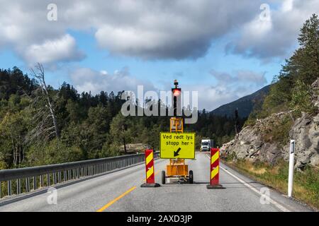 Road building traffic light signal. Mountain road stop here sign. Road works ahead. Nice sky clouds landscape Stock Photo