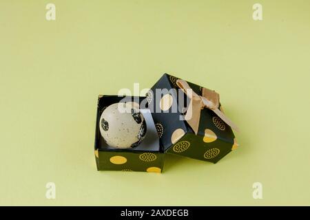 Gift or holiday box or container with colorful Easter eggs on a yellow background. Easter celebration concept in minimal style Stock Photo