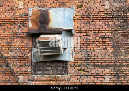 a rusty old air conditioner on a vintage red brick wall Stock Photo