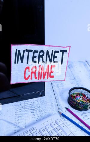 Handwriting text writing Internet Crime. Conceptual photo crime or illegal online activity committed on the Internet Note paper taped to black compute Stock Photo