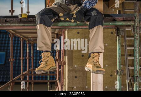 Working on a Scaffolding. Construction Worker Taking Short Break. Industrial Concept. Stock Photo
