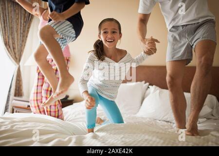 Family jumping on bed together Stock Photo