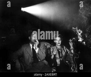 1951 : The movie actress GLORIA SWANSON ( Chicago 1898 - New York 1983 ) with WILLIAM HOLDEN in SUNSET BOULEVARD ( Viale del Tramonto ) by Billy Wilder, costume by Edith HEAD , Paramount pubblicity still - FILM - CINEMA - attrice cinematografica - VAMP -  DIVA - DIVINA - DIVINE - Hollywood on Hollywood - fumo - smoke - smoker - fumatore - fumatori - sigaretta - cigarette - sala cinematografica - proiezione - cravatta - tie - necklace - collana ----  Archivio GBB Stock Photo