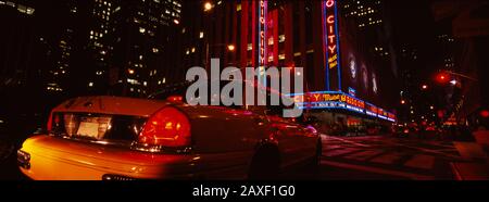 Car on a road, Radio City Music Hall, Rockefeller Center, Manhattan, New York City, New York State, USA Stock Photo