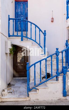 3 cats laying down on stairs with blue railing in front of a traditional Greek house in Skala Eressos on the island of Lesvos Stock Photo
