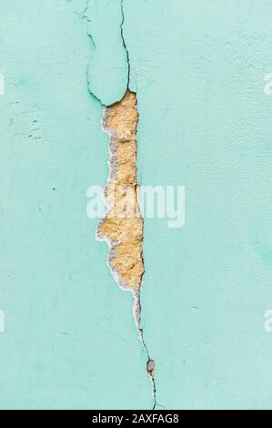 Closeup shot of a crack and chip on a blue concrete wall Stock Photo