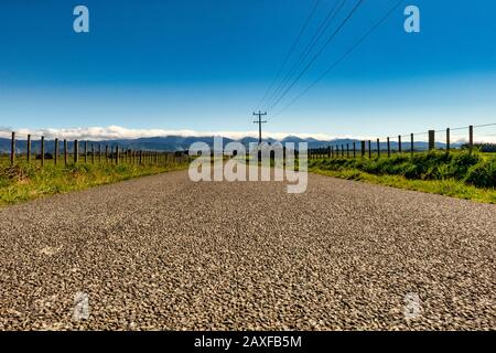 Low perspective of Long straight country road heading for the Tararua Ranges not a car in sight Stock Photo