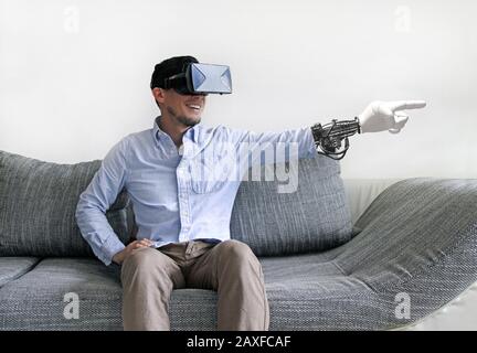 Male in virtual reality headset pointing with his robotic arm isolated on white background Stock Photo