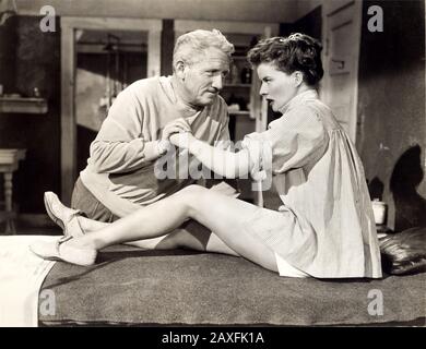 1952 , USA : The movie actress KATHARINE HEPBURN ( 1907 - 2003 )  with SPENCER TRACY in PAT AND MIKE ( Lui e Lei ) by George Cukor , from a story by Ruth Gordon - COMEDY -  FILM  - DIVA - DIVINA - massage - massaggio - legs - gambe - leggy pose - profilo - profile - lotta - fight - camicia - shirt - coppia - duo - couple - innamorati - amanti - lovers  © Archivio GBB / Stock Photo