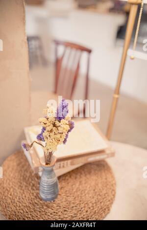 vase dry bouquet of flowers and books with warm light in room Stock Photo