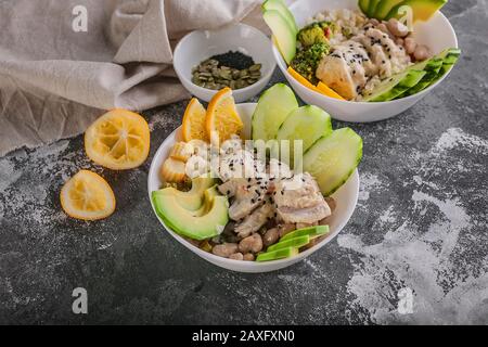 Close up Buddha bowl with chicken meat, bulgur, white beans, quinoa, avocado, lemon and fresh cucumber. Stock Photo