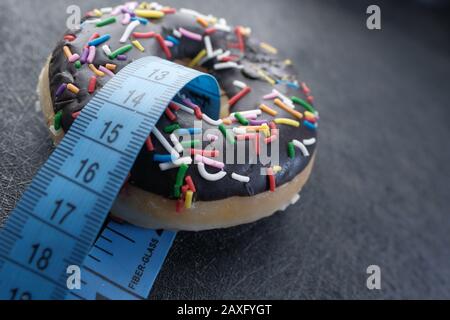 Close up of measurement tape and donut on table  Stock Photo