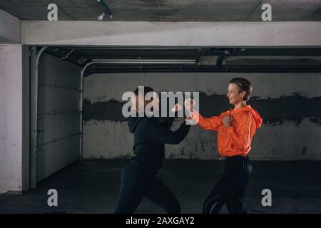 Two female athletes showing technical skills while practicing fighting in a garage Stock Photo