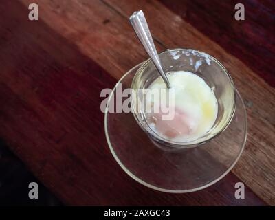 Soft-boiled eggs in glass with spoon on wooden table background top view. Stock Photo