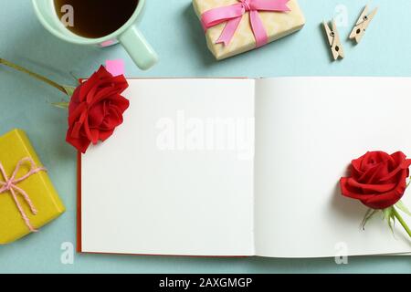 Empty note paper with red rose flower, black coffee, gift boxes on mint green background. Flat lay, top view, copy space Stock Photo