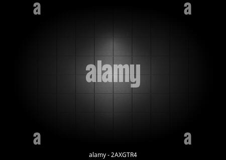 Light shining down on black ceramic tile wall in dark room with copy space, abstract background Stock Photo