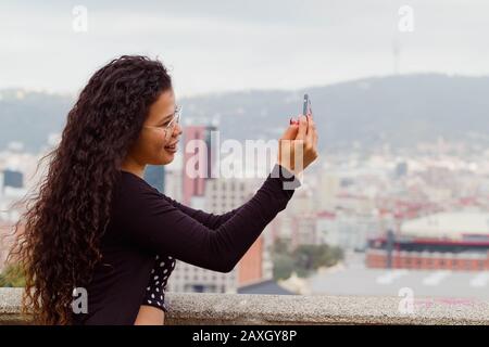 Attractive woman tourist taking a selfie, cityscape on the background Stock Photo