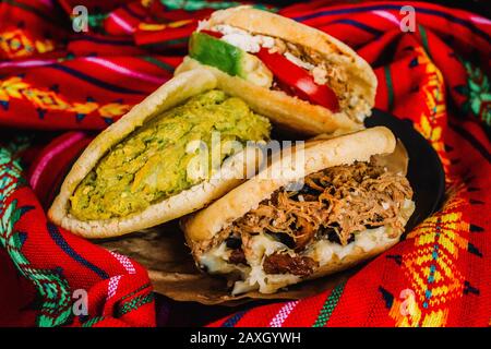 Venezuelan arepas on a colorful background, made with maize and filled with avocado, tomato, meat, cheese and black beans Stock Photo