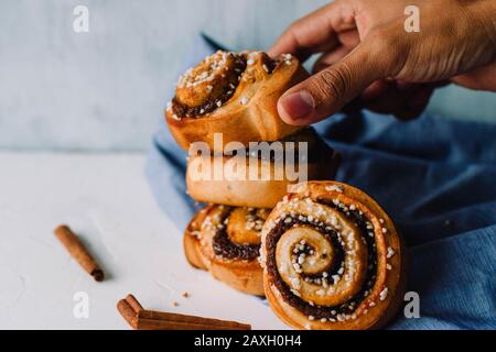 Hand holding cinnamon rolls on a white background Stock Photo