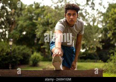 Stretching in a park. Young latin man doing exercices after running Stock Photo