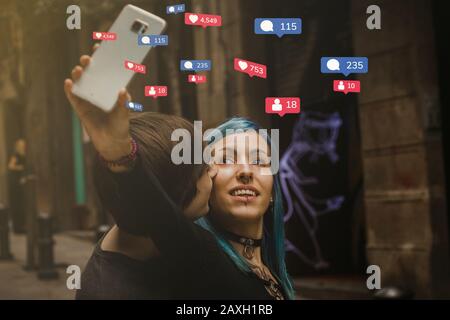 Social media addiction concept: A couple of millenials taking pictures with the smartphone on a street, teenagers lifestyle Stock Photo