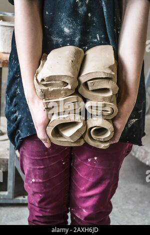 Master potter girl holding a many cut and twisted layers roll of clay pieces. Creative studio potter. Workplace wizard Crock pottery Stock Photo