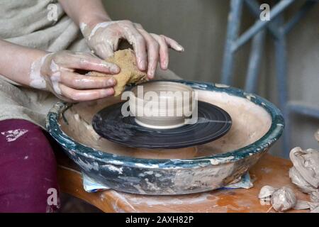 person potter makes clay jug on a potter's wheel in pottery workshop Stock Photo