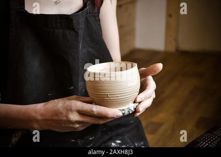 A raw clay pot in the hands of a potter. Master crock. Stock Photo