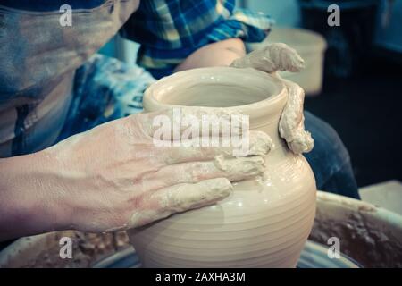 The potter molds clay jug pot closeup. Workshop on sculpt white clay closeup. Dirty hands in the clay. Making ceramic products . Artistic creative. Stock Photo