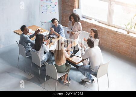 Ellegant afro woman speaking to colleagues, making business report Stock Photo