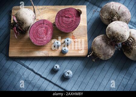 High angle shot of cut and whole beetroot with berries on a chopping board Stock Photo