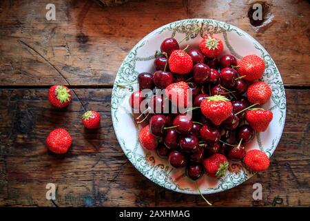Plate with cherries and strawberries on a wooden table Stock Photo