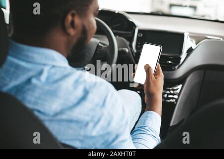 Man Using Phone With Empty Screen Sitting In Car, Back-View Stock Photo