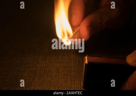 Match is ignited by striking the head against a match box Stock Photo
