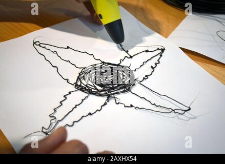 Man 3d pen draws a flower on white paper close-up, Stock Photo