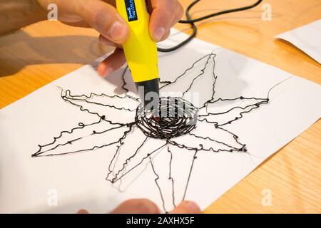 Man 3d pen draws a flower on white paper close-up, Stock Photo