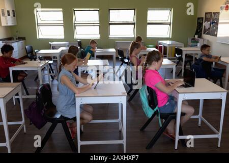 Group of schoolchildren sitting at desks in an elementary school ...