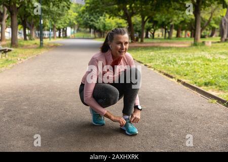 Female jogger tying her shoe laces in the park Stock Photo