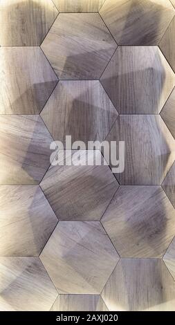 3D decorative wall with imitation wood texture for the interior of an unusual hexagonal geometric shape similar to honeycombs. Gray-brown light backgr Stock Photo